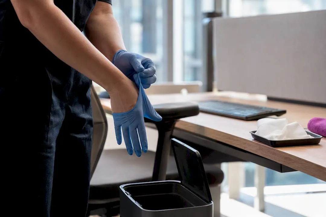 Cleaner changing gloves beside shared desk